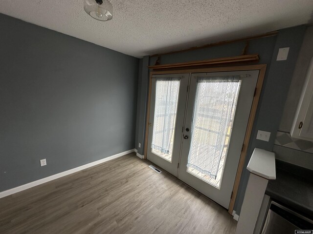 3649 Campbell Dr, Torrington, WY 82240 - doorway to outside with french doors, wood finished floors, a textured ceiling, baseboards, and visible vents