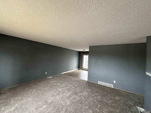 3649 Campbell Dr, Torrington, WY 82240 - spare room featuring baseboards, carpet floors, a textured ceiling, and visible vents