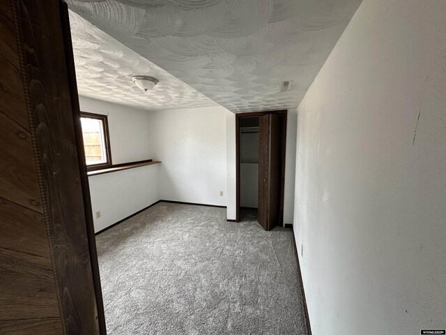 3649 Campbell Dr, Torrington, WY 82240 - unfurnished bedroom featuring light carpet, baseboards, visible vents, and a textured ceiling