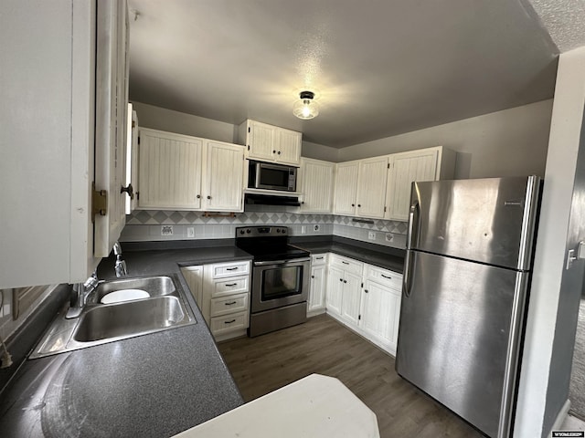 3649 Campbell Dr, Torrington, WY 82240 - kitchen featuring stainless steel appliances, dark wood finished floors, backsplash, a sink, and dark countertops