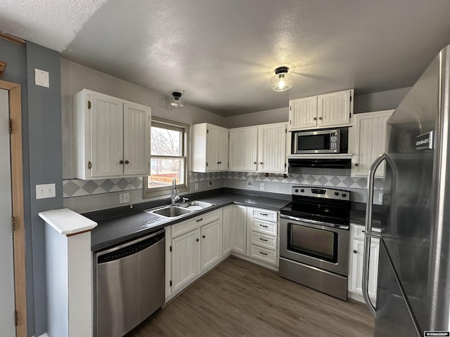 3649 Campbell Dr, Torrington, WY 82240 - kitchen featuring stainless steel appliances, dark countertops, dark wood-type flooring, white cabinetry, and a sink