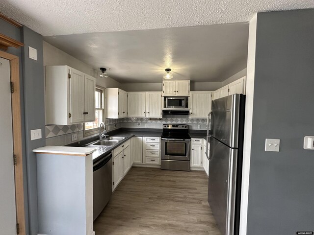 3649 Campbell Dr, Torrington, WY 82240 - kitchen with decorative backsplash, a sink, stainless steel appliances, and wood finished floors