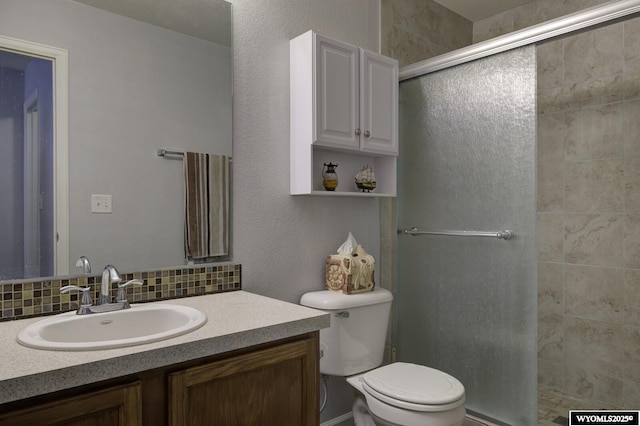 bathroom featuring backsplash, vanity, toilet, and a stall shower