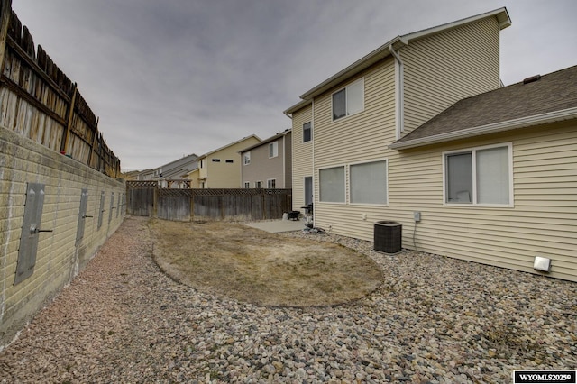rear view of property with cooling unit, a patio, and a fenced backyard