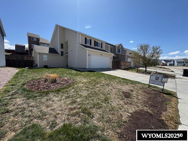 view of front facade with driveway, fence, a front yard, and a garage