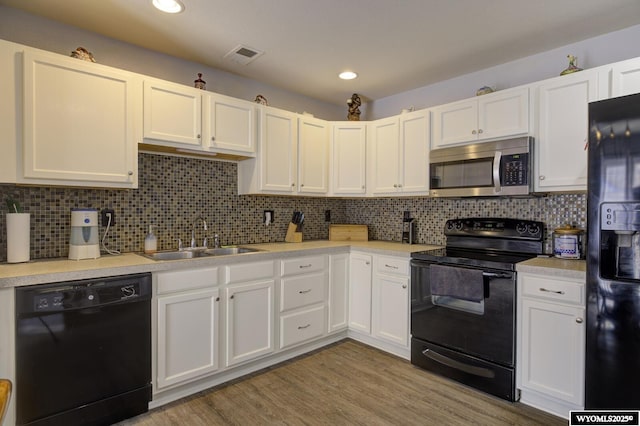 kitchen featuring a sink, black appliances, light countertops, white cabinetry, and visible vents