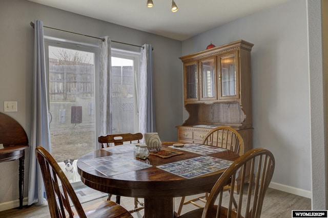dining space with baseboards and light wood finished floors