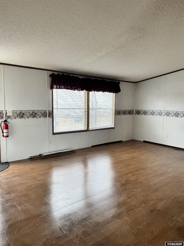unfurnished room with wood finished floors and a textured ceiling