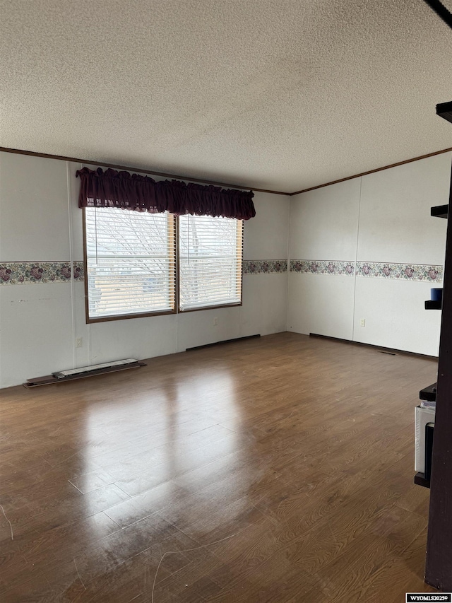 empty room featuring ornamental molding, wood finished floors, and a textured ceiling