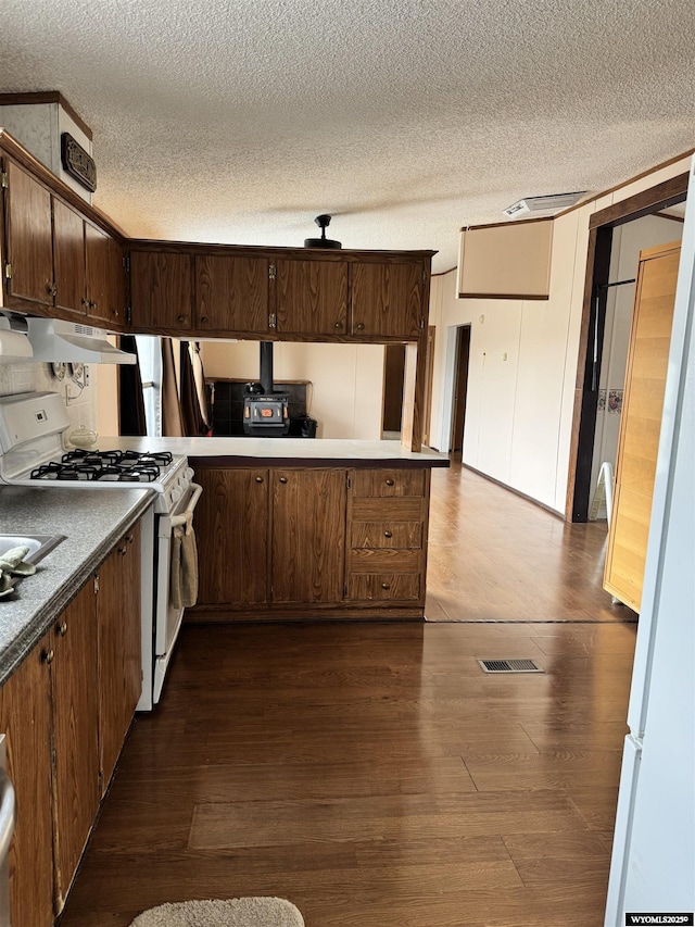 kitchen with white gas range oven, a textured ceiling, and dark wood-type flooring