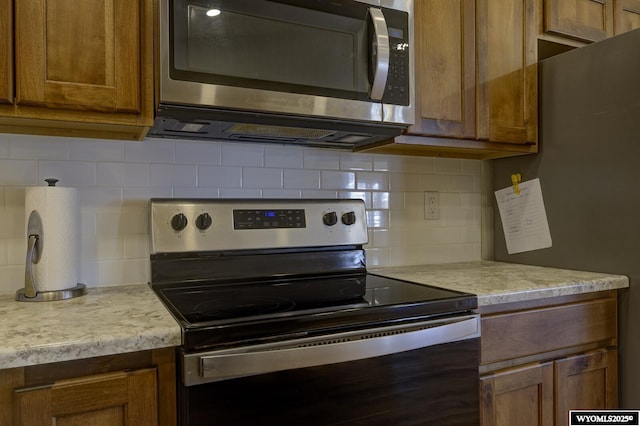 2087 Basswood St, Casper, WY 82604 - kitchen with brown cabinets, backsplash, light countertops, and appliances with stainless steel finishes
