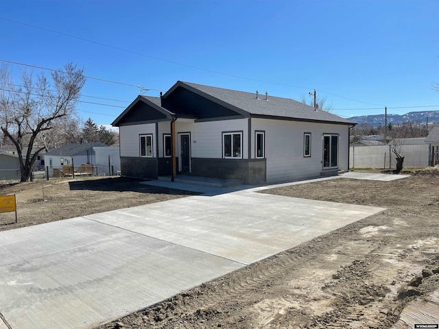 view of front of property with roof with shingles and fence