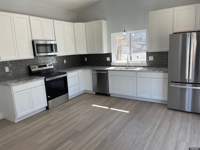 kitchen with appliances with stainless steel finishes, white cabinetry, and a sink