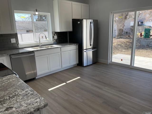 kitchen featuring backsplash, white cabinetry, stainless steel appliances, and a sink