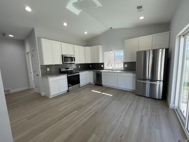 kitchen featuring a sink, decorative backsplash, stainless steel appliances, white cabinetry, and visible vents