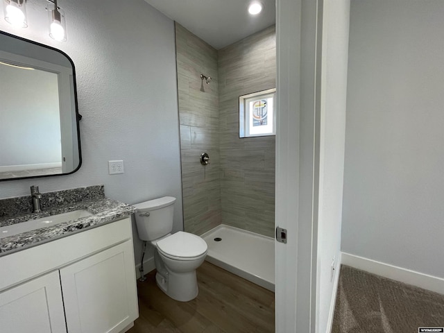 full bathroom with vanity, toilet, baseboards, and tiled shower