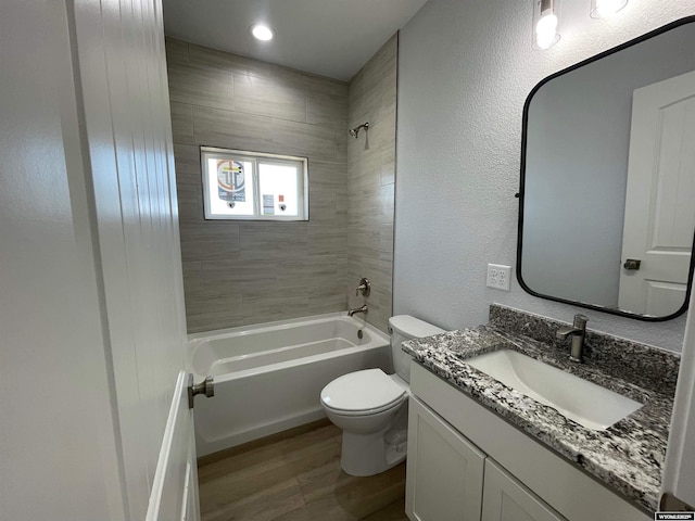 full bath with bathing tub / shower combination, toilet, wood finished floors, a textured wall, and vanity