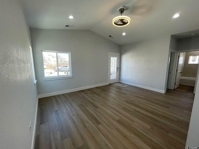 unfurnished bedroom featuring visible vents, wood finished floors, lofted ceiling, and multiple windows