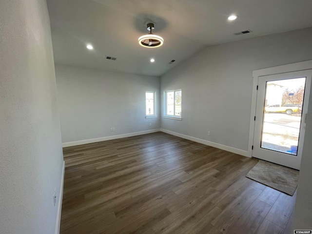 spare room featuring lofted ceiling, baseboards, wood finished floors, and visible vents