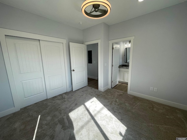 unfurnished bedroom with baseboards, ensuite bathroom, carpet flooring, and a closet