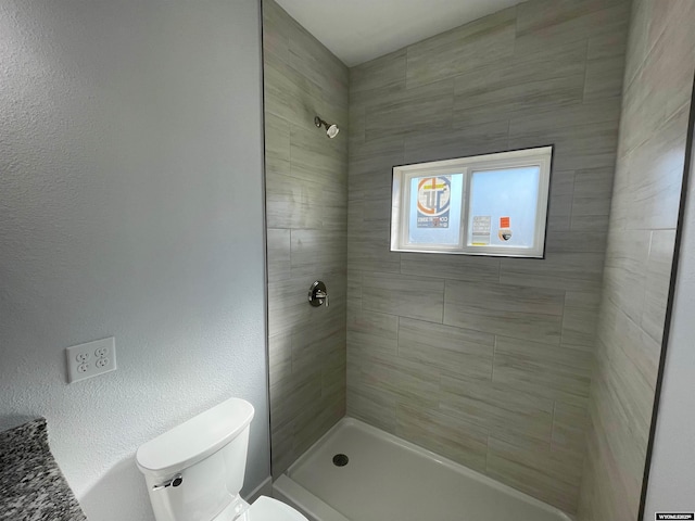 bathroom featuring a tile shower and toilet