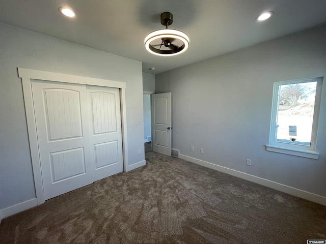 unfurnished bedroom with dark colored carpet, baseboards, visible vents, recessed lighting, and a closet