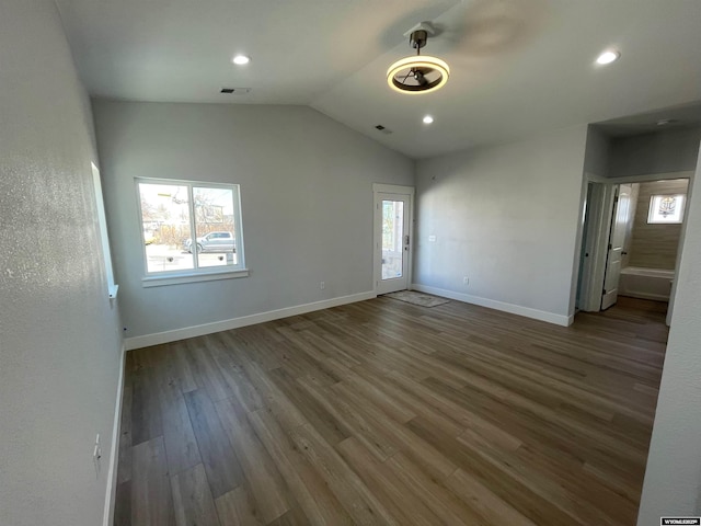unfurnished bedroom with wood finished floors, visible vents, lofted ceiling, and multiple windows