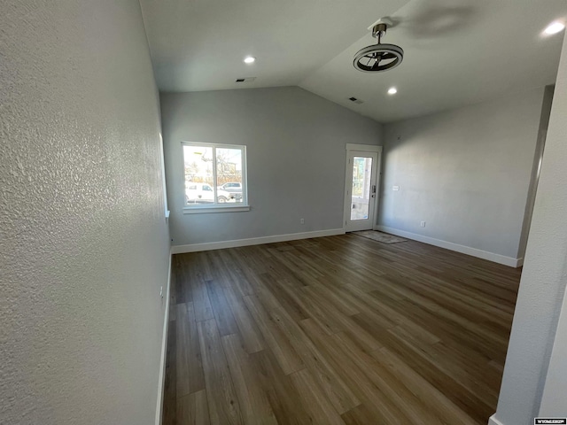 empty room with vaulted ceiling, wood finished floors, baseboards, visible vents, and recessed lighting
