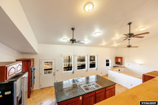 94 Upper Clear Creek Rd, Buffalo, WY 82834 - kitchen with a center island, stainless steel electric cooktop, reddish brown cabinets, ceiling fan, and light wood-style flooring