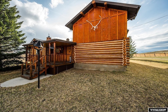 view of side of property featuring a chimney, a lawn, and log exterior
