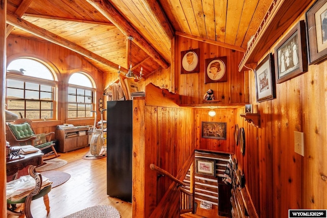 interior space with wooden ceiling, an upstairs landing, vaulted ceiling with beams, wood finished floors, and wood walls