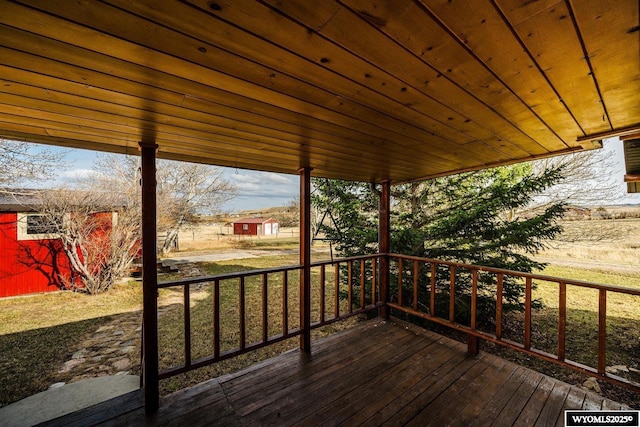 wooden terrace featuring an outdoor structure and a shed