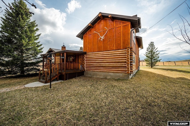 back of property featuring a chimney, board and batten siding, a yard, and log exterior