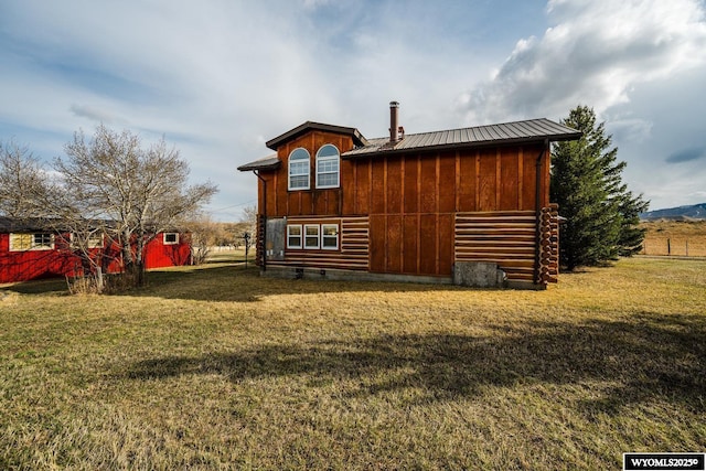 rear view of house with a lawn, metal roof, and board and batten siding