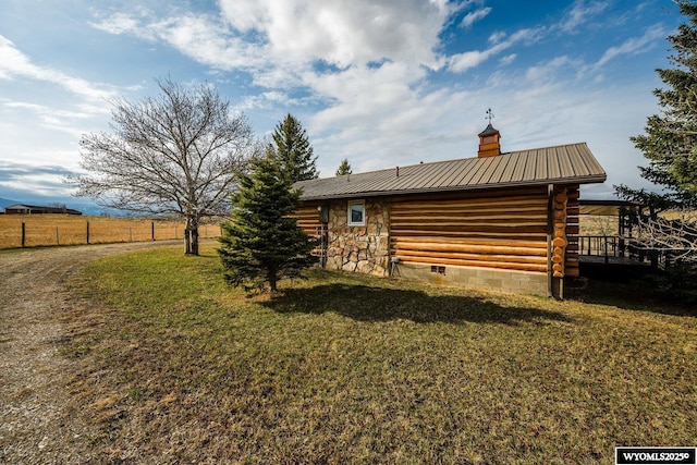exterior space featuring stone siding, metal roof, a yard, and a chimney