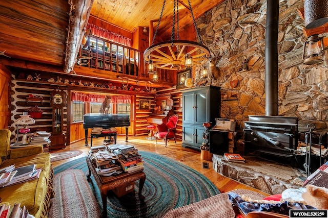living room featuring a wood stove, log walls, wood ceiling, a towering ceiling, and wood finished floors