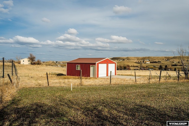 view of outdoor structure with an outdoor structure, fence, and a rural view