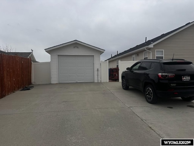detached garage featuring fence and concrete driveway