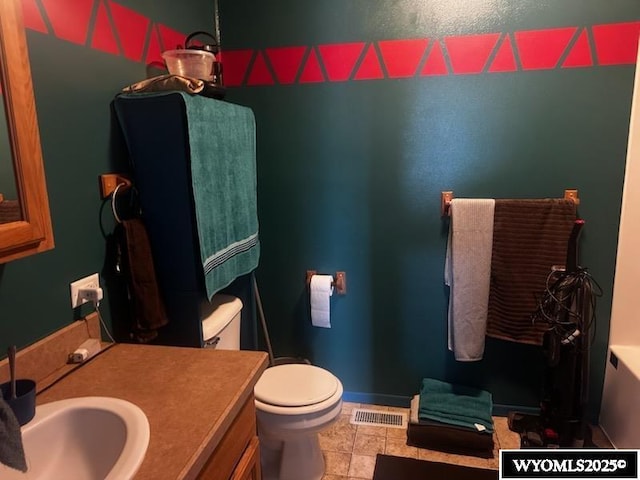 bathroom featuring baseboards, visible vents, toilet, and vanity