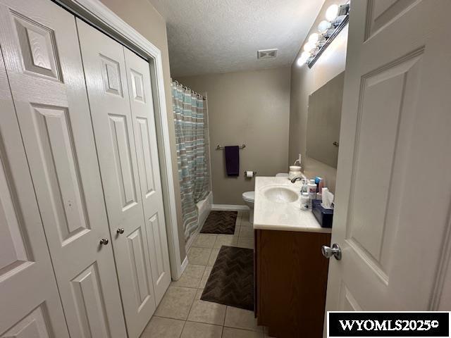 full bath featuring a textured ceiling, visible vents, toilet, vanity, and tile patterned flooring