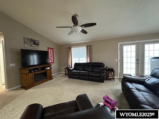 living area with light carpet, baseboards, vaulted ceiling, and ceiling fan