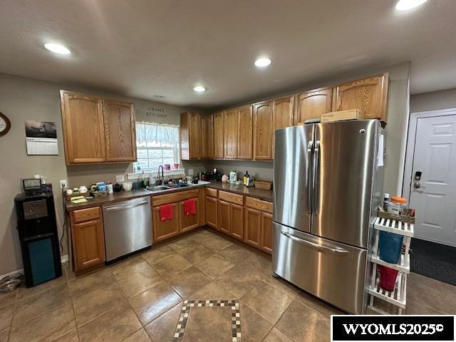 kitchen with a sink, dark countertops, appliances with stainless steel finishes, and recessed lighting
