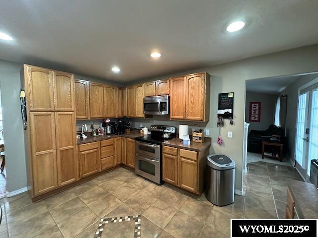 kitchen featuring baseboards, stainless steel appliances, recessed lighting, and dark countertops