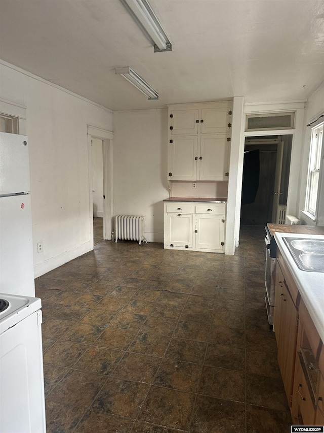 214 M St, Rock Springs, WY 82901 - kitchen with light countertops, a sink, white cabinetry, radiator heating unit, and white appliances