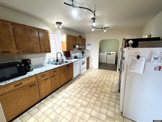 2842 Main St, Torrington, WY 82240 - kitchen with white appliances, arched walkways, under cabinet range hood, a sink, and washer and clothes dryer