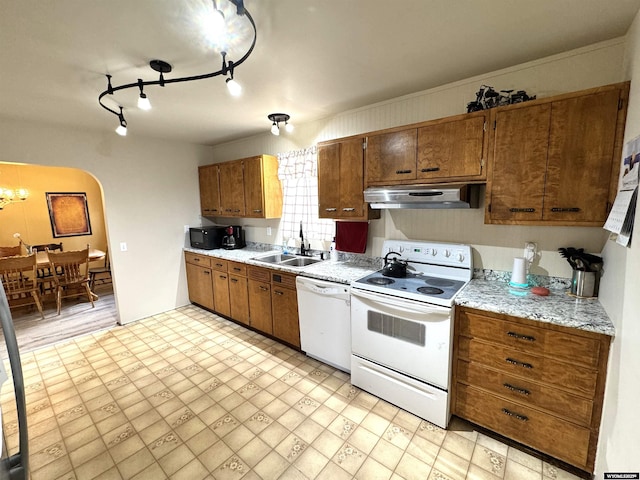 2842 Main St, Torrington, WY 82240 - kitchen with light countertops, a sink, under cabinet range hood, white appliances, and arched walkways