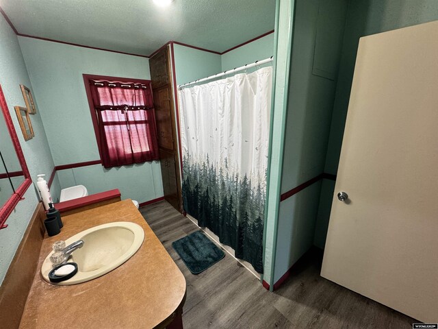 2842 Main St, Torrington, WY 82240 - bathroom featuring a textured ceiling, a shower with shower curtain, crown molding, wood finished floors, and vanity