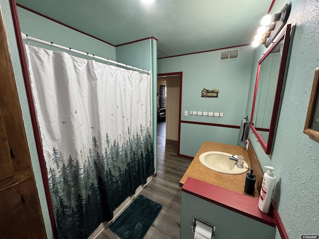 2842 Main St, Torrington, WY 82240 - bathroom featuring crown molding, vanity, wood finished floors, a textured ceiling, and visible vents