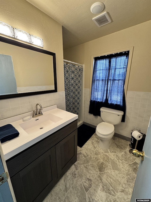 2842 Main St, Torrington, WY 82240 - bathroom featuring toilet, vanity, tile walls, and visible vents