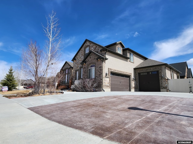 303 Tamarack Dr, Rock Springs, WY 82901 - traditional-style house with stone siding, fence, stucco siding, and concrete driveway